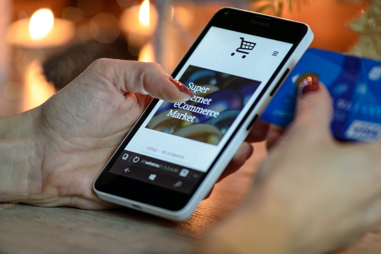 A person holding a phone in hand with eCommerce store open in browser
