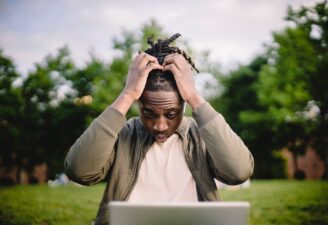 stressed black male entrepreneur working on laptop in park