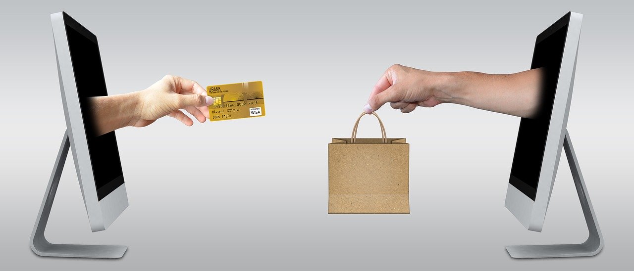 Two hands coming out of computers, one is holding a bag and the other is holding a credit card